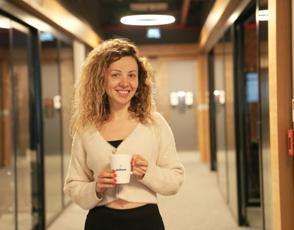 a woman holding a cup of coffee in a hallway